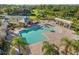 Aerial view of community pool and splashpad area surrounded by lush landscaping and lounge chairs at 11410 57Th E St, Parrish, FL 34219