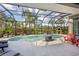 Beautiful screened-in pool area with lush landscaping, a wood-fired pizza oven, and comfortable seating at 11410 57Th E St, Parrish, FL 34219