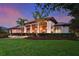 Majestic home at dusk showcasing landscape lighting and vibrant flower beds at 11807 Rive Isle Run, Parrish, FL 34219