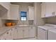 Functional laundry room features white cabinets, granite countertops, and modern machines at 11807 Rive Isle Run, Parrish, FL 34219