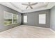 Spacious bedroom featuring two large windows, a tray ceiling, and light wood-style flooring at 11811 Fennemore Way, Parrish, FL 34219