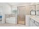 Bright bathroom featuring a soaking tub, separate glass-enclosed shower, and double sink vanity at 17536 Cantarina Cv, Bradenton, FL 34211