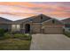 Charming single-story home with a two-car garage and stone accents under a beautiful orange sunset at 17536 Cantarina Cv, Bradenton, FL 34211