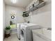 Functional laundry room with modern washer, dryer, shelving, sink, and a window with plantation shutters at 2152 Majestic Oaks Blvd, Clearwater, FL 33759