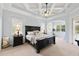 This primary bedroom features a coffered ceiling, fan, neutral carpet, and large bed with decorative pillows at 2152 Majestic Oaks Blvd, Clearwater, FL 33759