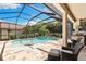 Relaxing screened-in pool and spa with travertine tile deck and outdoor kitchen, perfect for entertaining guests at 2152 Majestic Oaks Blvd, Clearwater, FL 33759