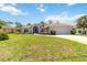 Beautifully landscaped single-story home with a two-car garage, lush green lawn, and a charming screened entryway at 251 Broadmoor Ln, Rotonda West, FL 33947