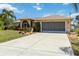 Charming home with a well-manicured front yard, lush landscaping, and a two-car garage at 2801 Dalhart Ave, North Port, FL 34286