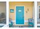 Bright turquoise front door with coastal decorations and seating on the screened porch at 2801 Dalhart Ave, North Port, FL 34286