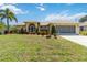 Beautiful single-story home with a well-manicured lawn, colorful plants and a two-car garage at 2801 Dalhart Ave, North Port, FL 34286