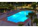 Nighttime view of a brightly lit community pool with mature landscaping and lounge chairs nearby at 3070 Grand Bay Blvd # 644, Longboat Key, FL 34228