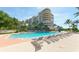 Relaxing pool area with lounge chairs at a condominium complex with tropical landscaping and blue skies at 3070 Grand Bay Blvd # 644, Longboat Key, FL 34228