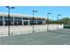The tennis court is in front of a clubhouse with tiered planters and manicured landscaping at 3070 Grand Bay Blvd # 644, Longboat Key, FL 34228