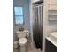 Well-lit bathroom featuring a toilet, shower with gray curtain, and a window for natural light at 3231 Cambridge Dr, Sarasota, FL 34232