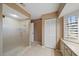 Bathroom featuring a walk-in shower with glass door, tiled floor, and a window with plantation shutters at 3335 Meadow Run Ter, Venice, FL 34293