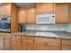 Well-equipped kitchen with wood cabinets, granite countertops, stainless steel appliances, and a built-in cooktop at 3335 Meadow Run Ter, Venice, FL 34293