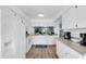 Bright kitchen with white cabinetry, modern appliances, and wood-look floors; view into the living room at 3703 5Th Ave # 3, Holmes Beach, FL 34217