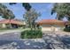 Charming villa with a red tile roof, two-car garage, brick driveway, and tropical landscaping at 5039 Kestral Park Dr # 67, Sarasota, FL 34231
