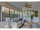 Bright sunroom features a comfortable sofa, ceiling fan, and natural light streaming through expansive windows at 5039 Kestral Park Dr # 67, Sarasota, FL 34231