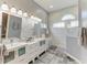 Well-lit bathroom boasts dual vanities, sleek mirrors, and a luxurious marble tiled shower at 5386 Creekside Trl, Sarasota, FL 34243