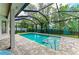 Screened pool with a brick-paved patio and tropical landscaping at 5386 Creekside Trl, Sarasota, FL 34243