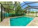 Inviting screened-in pool with brick surround and lush landscaping for privacy at 5386 Creekside Trl, Sarasota, FL 34243