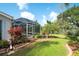 Backyard view with a screened-in lanai and lush tropical landscaping with vibrant plants at 5812 Garden Lakes Fern, Bradenton, FL 34203