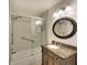 Bathroom features a shower with sliding glass doors, updated vanity, and bronze-framed round mirror at 5812 Garden Lakes Fern, Bradenton, FL 34203