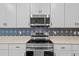 A stainless steel microwave and electric range are set among stylish white cabinets and designer backsplash at 5816 Mezzana Run, Palmetto, FL 34221