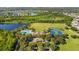 Aerial view of community amenities including swimming pool, tennis courts, and lush greenery near a serene lake at 5902 106Th E Ter, Parrish, FL 34219
