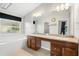Bright bathroom featuring a soaking tub, double vanity with wood cabinets, and a large mirror with vanity lighting at 5902 106Th E Ter, Parrish, FL 34219