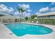 A bright blue community pool with a clear sky overhead near lush greenery and a cabana at 6546 Fairway Gardens Dr # 6546, Bradenton, FL 34203