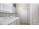 Bright laundry room with side-by-side washer and dryer, white shelving, and door to closet at 6721 Oak Manor Dr, Lakewood Ranch, FL 34202