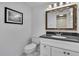 Bathroom features a black countertop, and white cabinets, toilet and a decorative mirror at 7308 Maryland Ave, Hudson, FL 34667