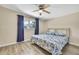 Bright bedroom features a ceiling fan, wood floors, and a window with blue curtains at 7308 Maryland Ave, Hudson, FL 34667