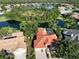 Aerial shot showcasing a home's backyard pool, set among mature trees and neighboring houses, with a view of a pond at 766 Shadow Bay Way, Osprey, FL 34229