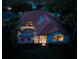 Aerial night shot showcases the home's screened pool and lanai, with interior lights glowing warmly and lush landscaping at 766 Shadow Bay Way, Osprey, FL 34229