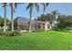 A sprawling backyard with a screened-in pool and a well-manicured lawn, surrounded by lush landscaping and palm trees at 766 Shadow Bay Way, Osprey, FL 34229