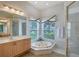 Bathroom featuring a jacuzzi bathtub, a large mirror, and a glass-enclosed shower at 766 Shadow Bay Way, Osprey, FL 34229