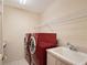 A laundry room with a red washer and dryer, white sink and wire shelving at 766 Shadow Bay Way, Osprey, FL 34229
