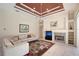 Bright living room showcasing tray ceilings, built-in shelving, and a cozy fireplace at 766 Shadow Bay Way, Osprey, FL 34229