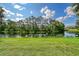 Scenic view of lush lawn leading to a tranquil pond with reflecting trees under a blue sky with scattered clouds at 766 Shadow Bay Way, Osprey, FL 34229