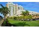 Beautiful condo building boasting a meticulously landscaped lawn and mature trees against a clear blue sky at 800 N Tamiami Trl # 317, Sarasota, FL 34236
