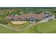 Aerial view of the large clubhouse with manicured landscaping, golf course, and parking area in a residential community at 8735 Olde Hickory Ave # 8205, Sarasota, FL 34238