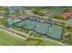 Aerial view of four tennis courts, a pool, and parking at the community center surrounded by mature landscaping at 8735 Olde Hickory Ave # 8205, Sarasota, FL 34238