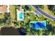 An aerial view showcases the pool, tennis court, and lush green landscaping of the community at 8755 Olde Hickory Ave # 7105, Sarasota, FL 34238