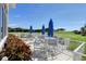 Outdoor patio area with tables, chairs, and umbrellas overlooking a scenic golf course at 8755 Olde Hickory Ave # 7105, Sarasota, FL 34238