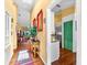 Inviting hallway with hardwood floors, yellow walls, and a view into the kitchen with white cabinets and a green door at 1312 Perico Point Cir, Bradenton, FL 34209