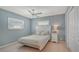 Relaxing blue bedroom features a ceiling fan, two windows, and neutral colored carpet at 1461 Porpoise Rd, Venice, FL 34293