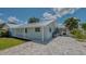 Side angle of a light blue single-story home with silver metal roof and gray brick driveway at 1461 Porpoise Rd, Venice, FL 34293